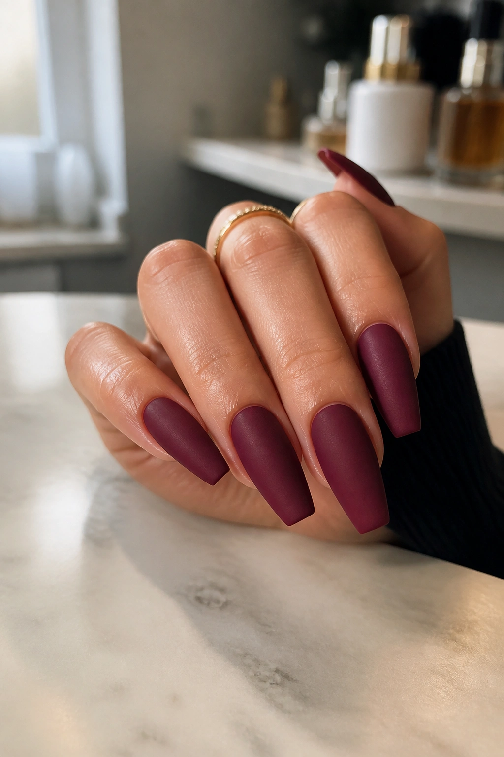 Hand with matte burgundy nails in soft light showing matte finish