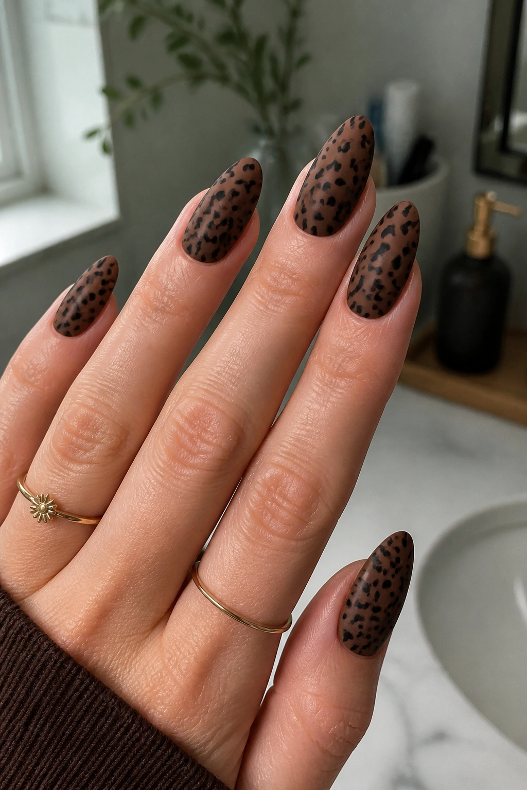 Long almond nails in matte cocoa with cheetah spots under natural light