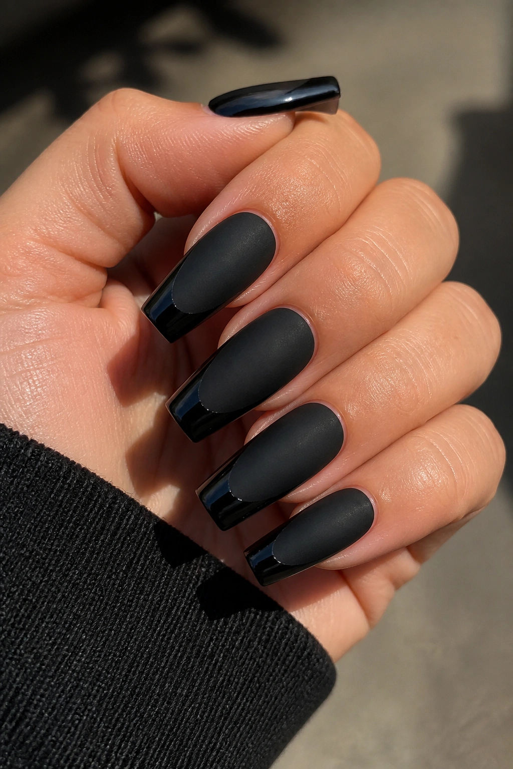 Close-up of real hand with matte black coffin nails and glossy French tips