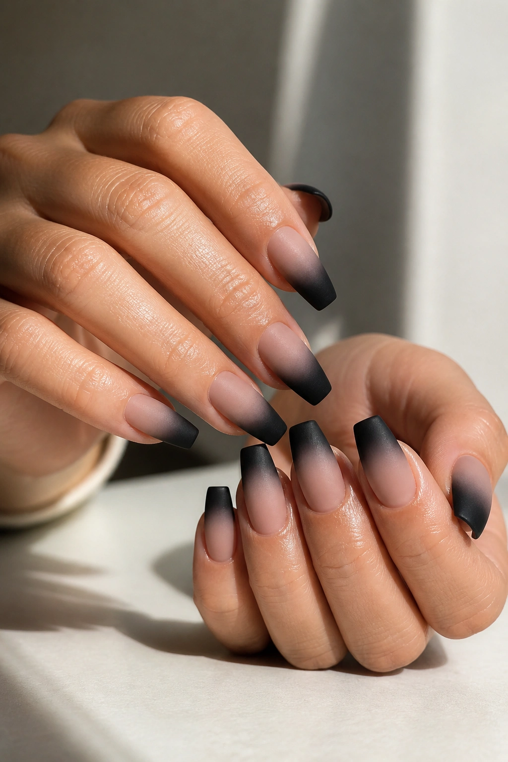 Close-up of medium coffin nails with matte nude-to-black fade