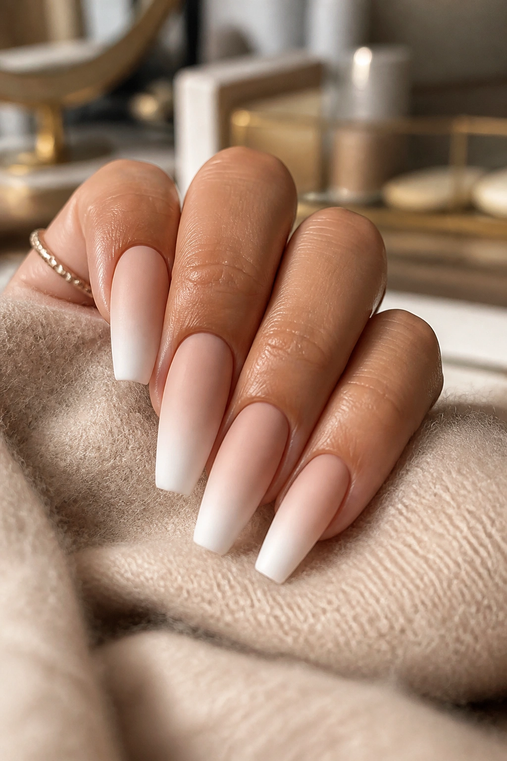 Close-up of matte cashmere white ombre coffin nails on a hand.