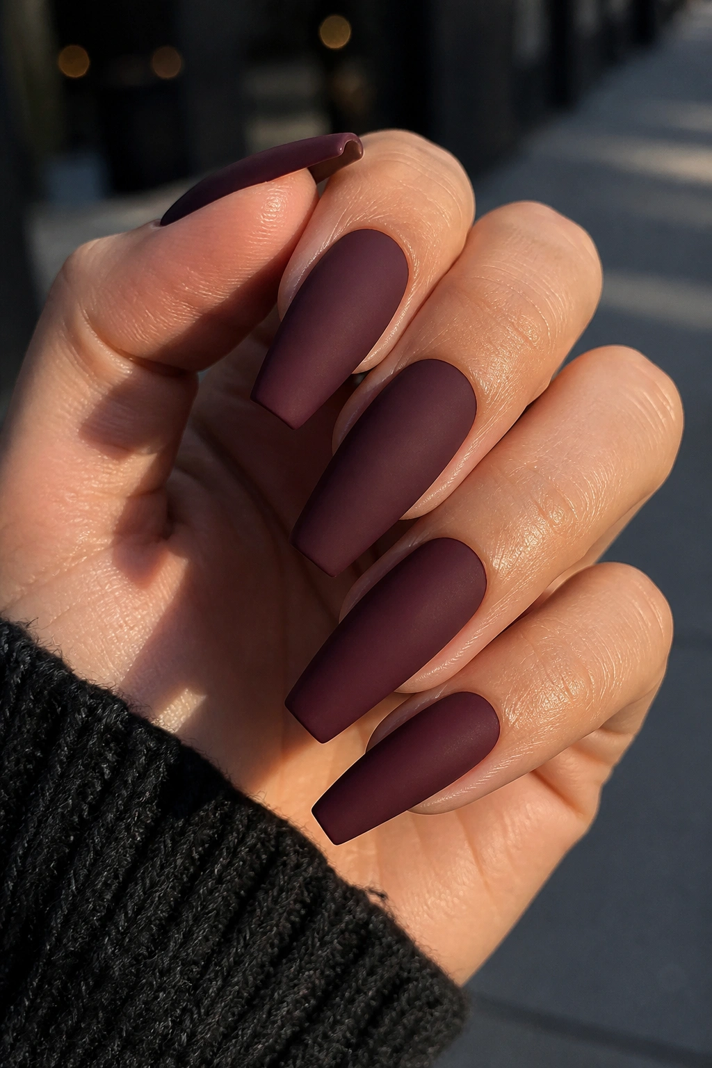 Close-up of matte oxblood coffin nails on a real hand.