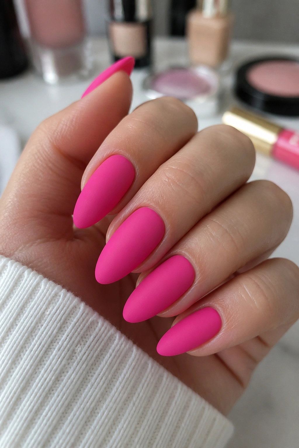 Close-up of matte hot pink almond nails on a real hand