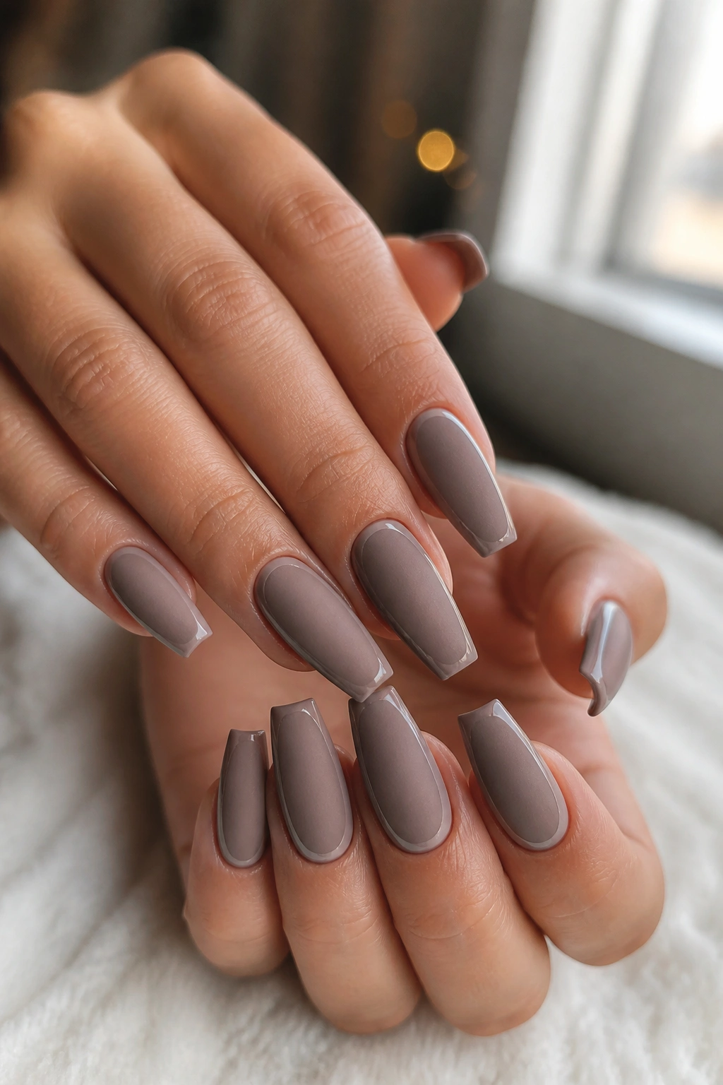 Close-up of medium coffin nails with matte taupe base and glossy outline on real hands