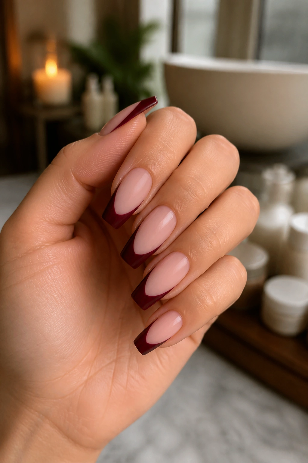 Close-up of coffin nails with matte wine red tips on milky pink base