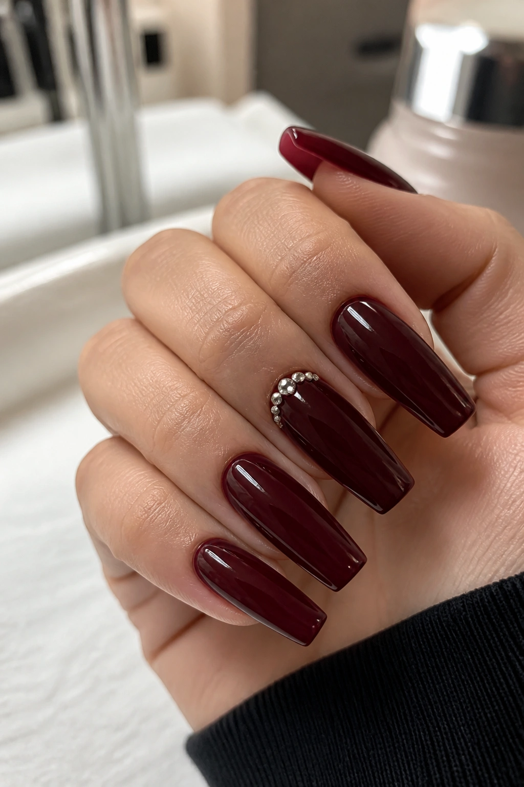 Close-up burgundy coffin nails with micro crystals at the cuticle on a real hand