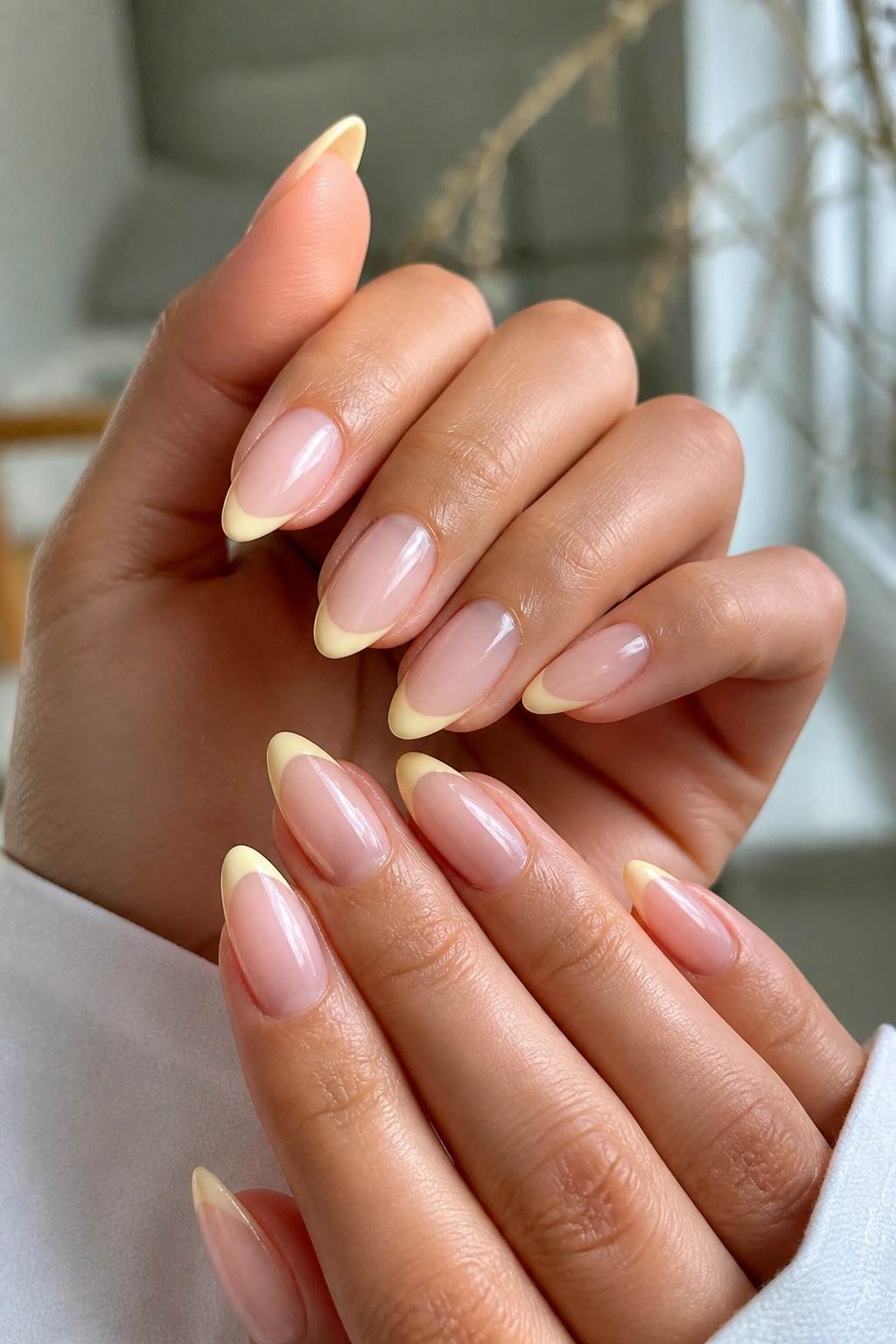 Close-up of almond nails with yellow micro French tips on a real person’s hands