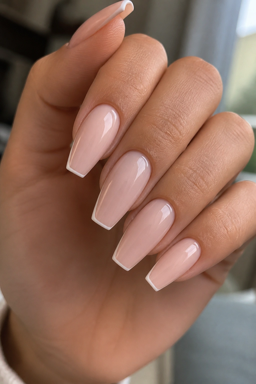 Close-up of a hand with micro-French coffin nails featuring a 1 mm white tip on milky nude base