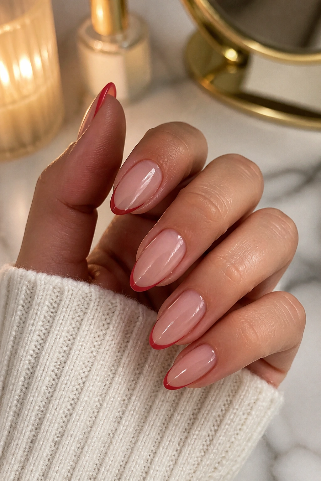 Close-up of a hand with thin red micro-French tips on almond nails.