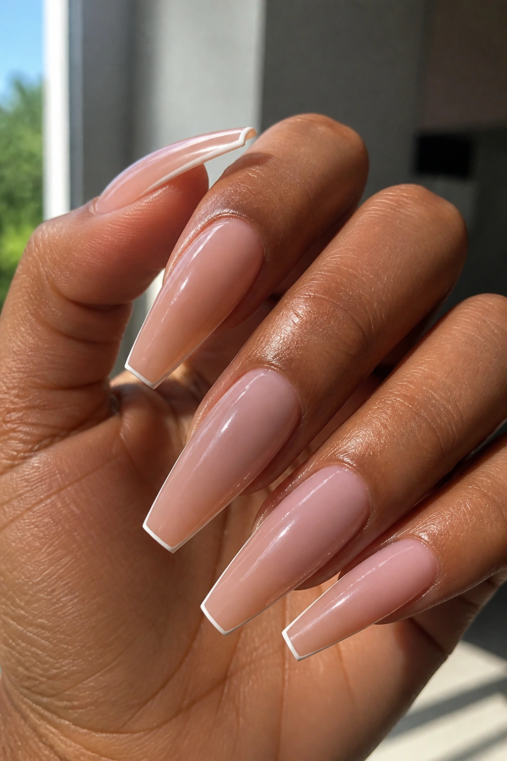 Close-up of long coffin nails with micro French tips on a real hand in a salon