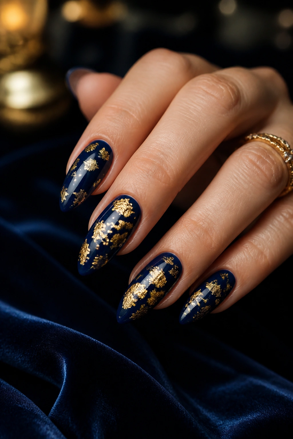 Close-up of midnight blue almond nails with gold foil flecks