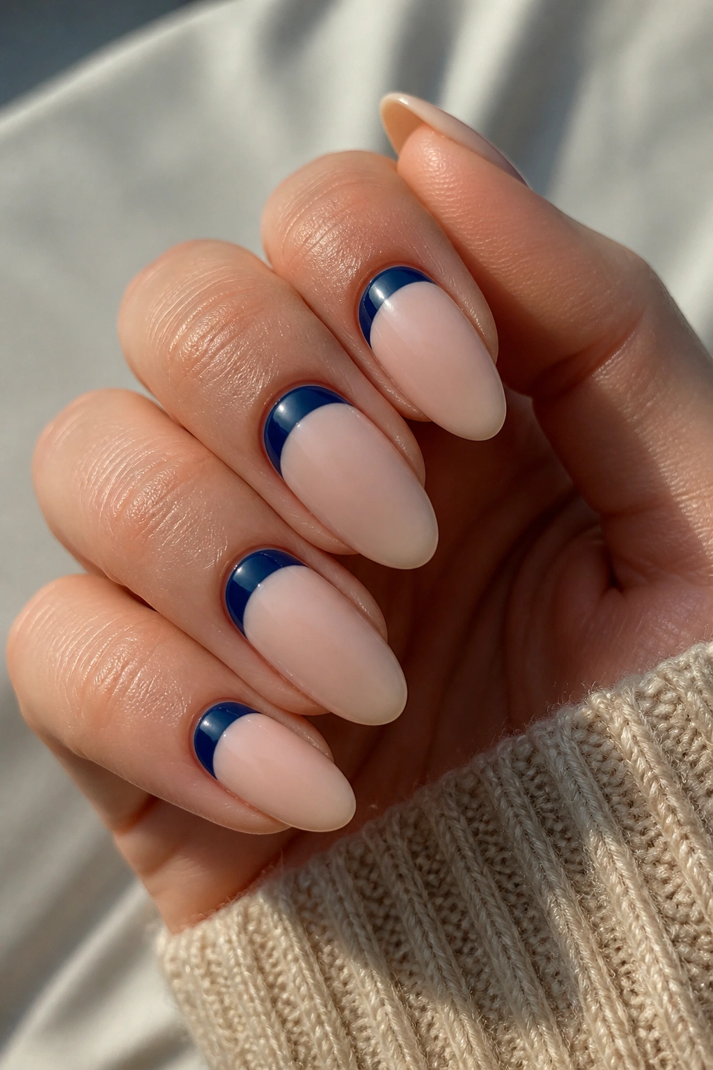 Almond nails with midnight blue half-moons near the cuticle close-up.