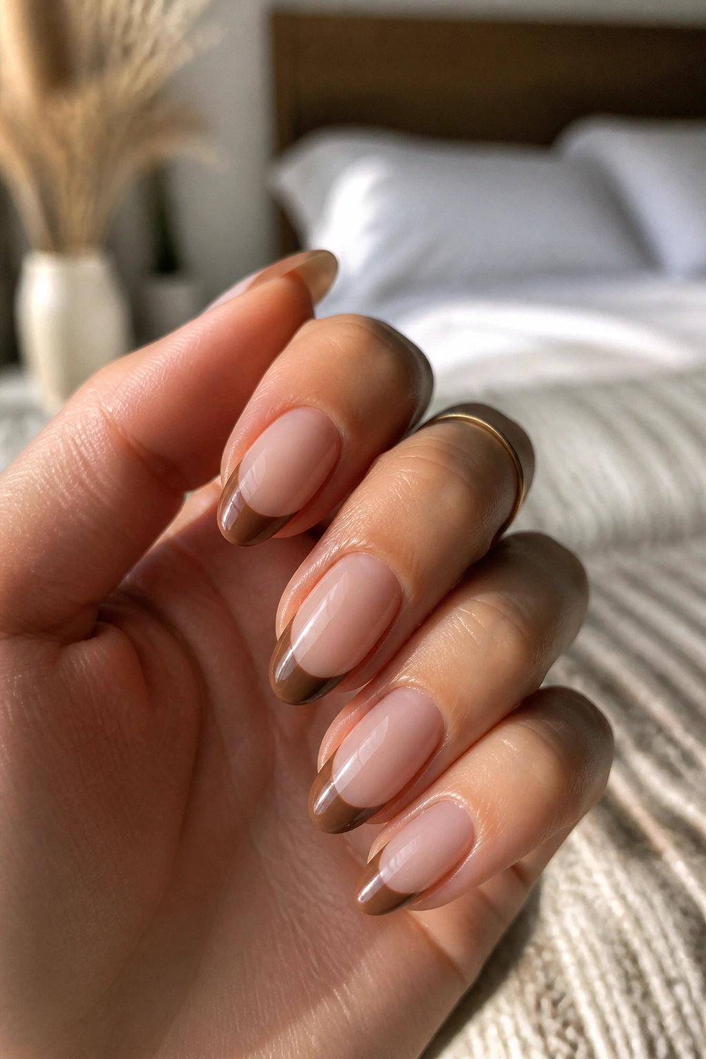 Close-up of almond nails with milk chocolate half-moon French tips on a nude base