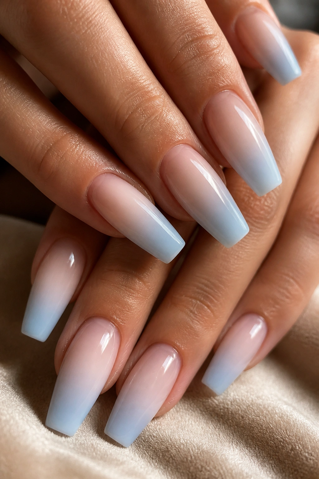 Close-up of milky light blue ombre coffin nails with sheer nude base on real hand
