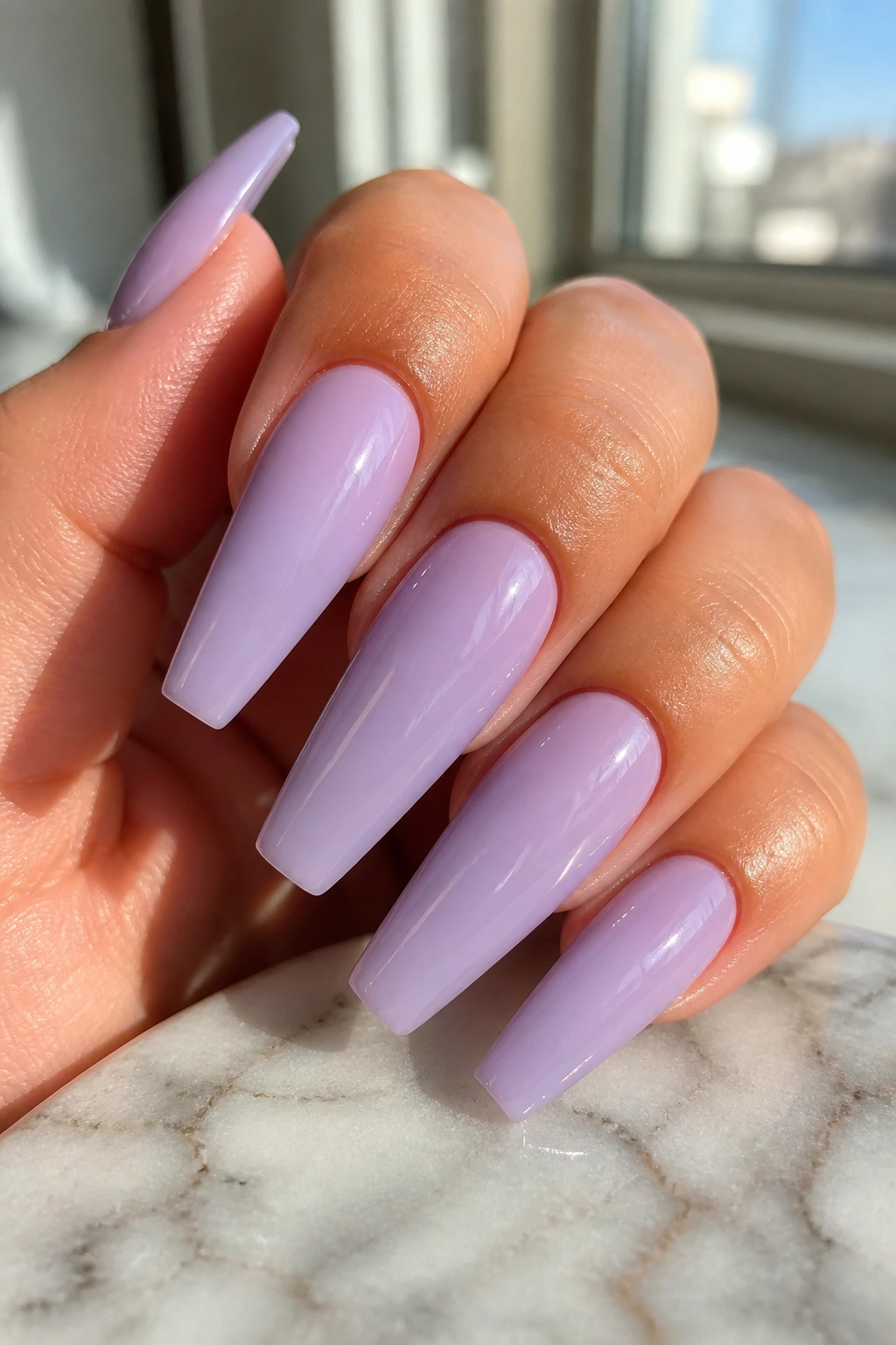 Close-up of milky lilac coffin nails on a real hand with glossy finish
