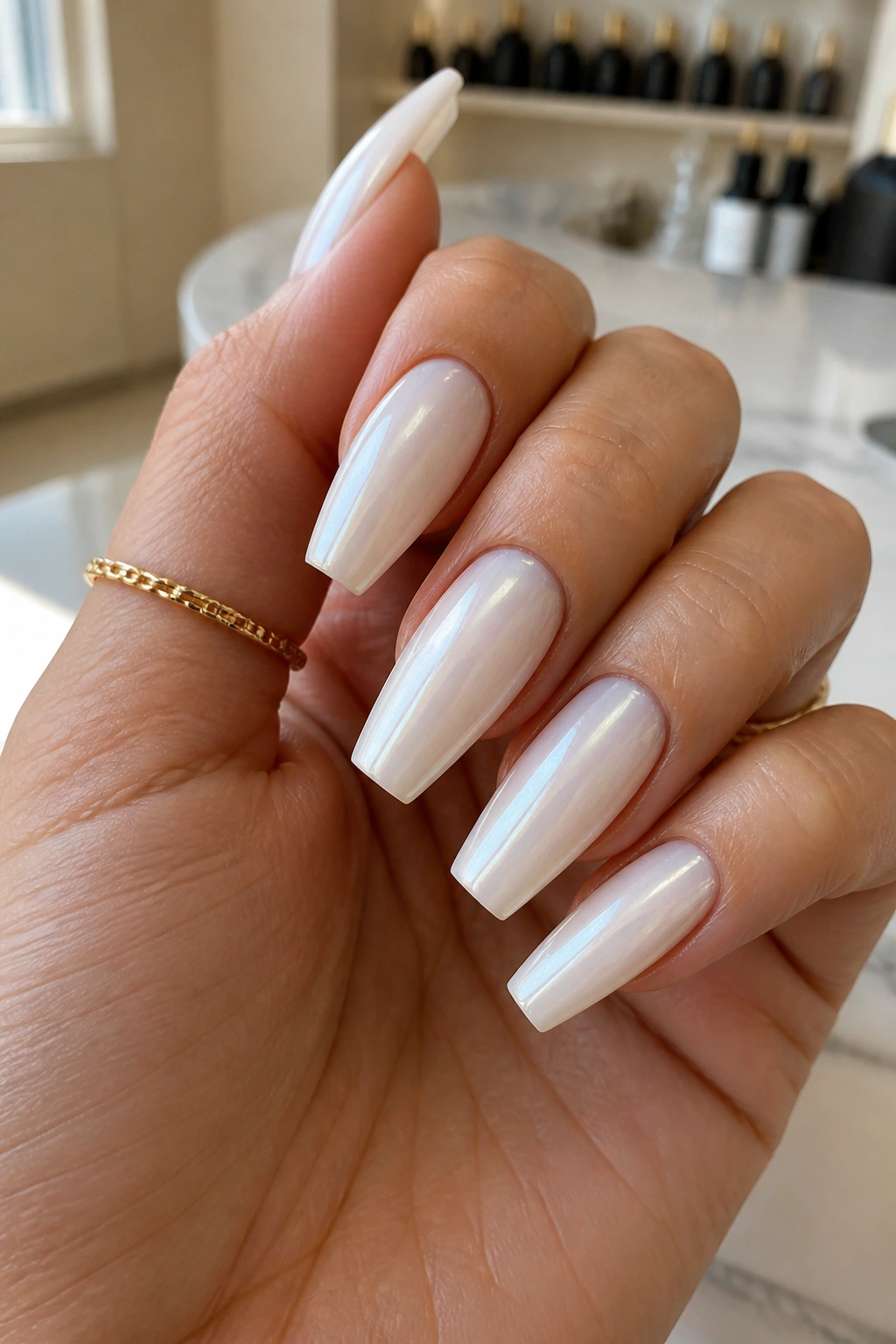 Close-up of milky white coffin nails with pearl chrome sheen on a real hand in a salon