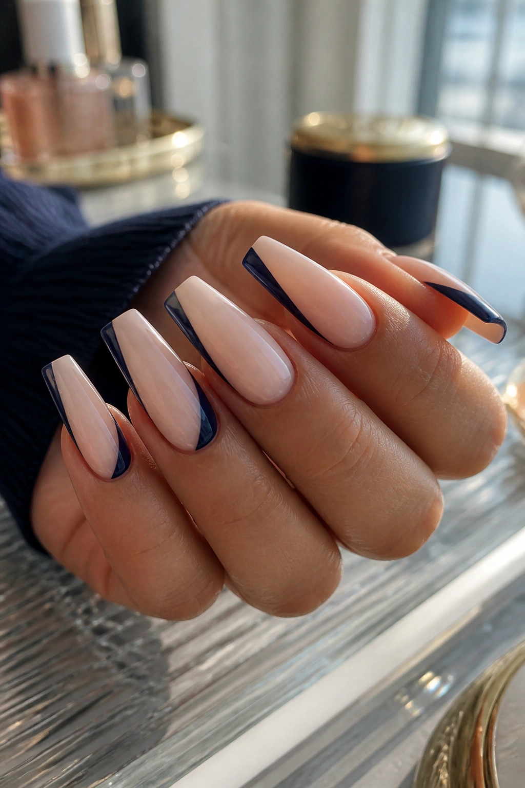 Milky nude coffin nails with navy side sweep on a real hand near a window
