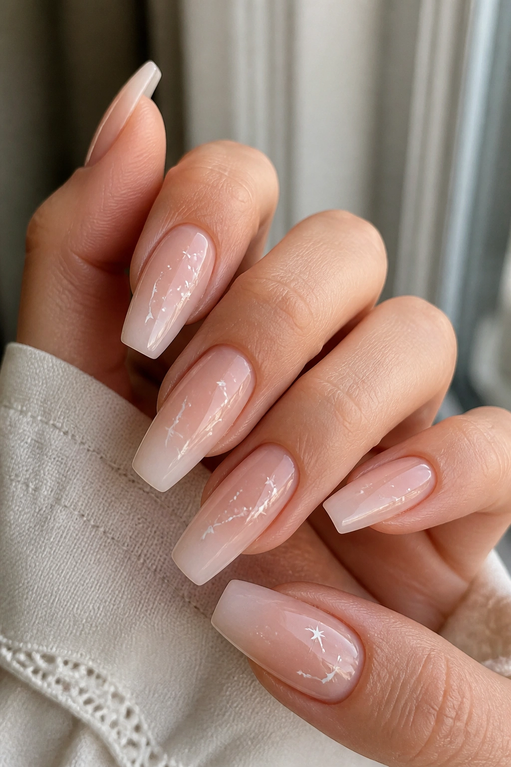 Milky nude ombre nails with tiny white constellations on real hands