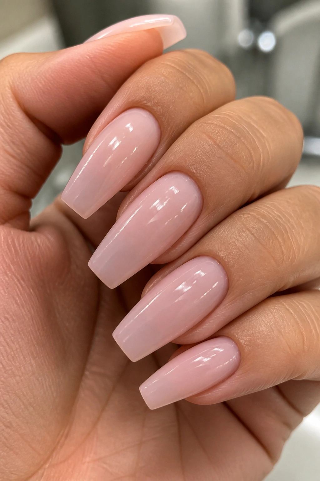 Milky pink coffin nails close-up with translucent finish