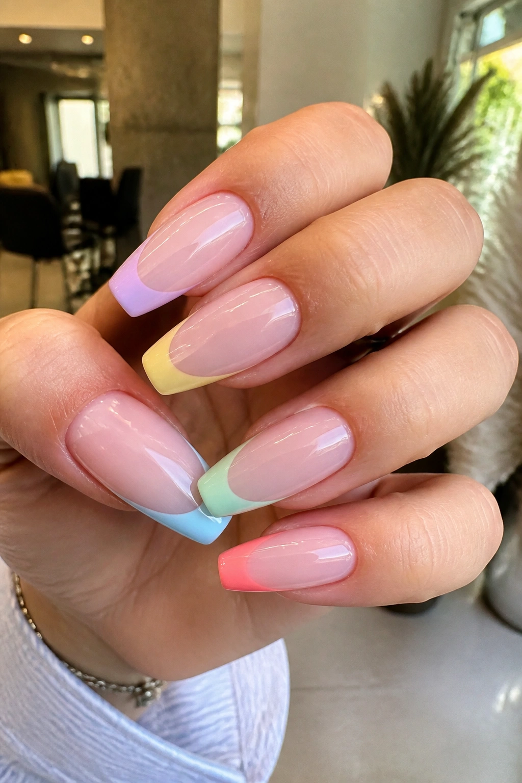 Close-up of milky pink coffin nails with mixed candy-colored tips.