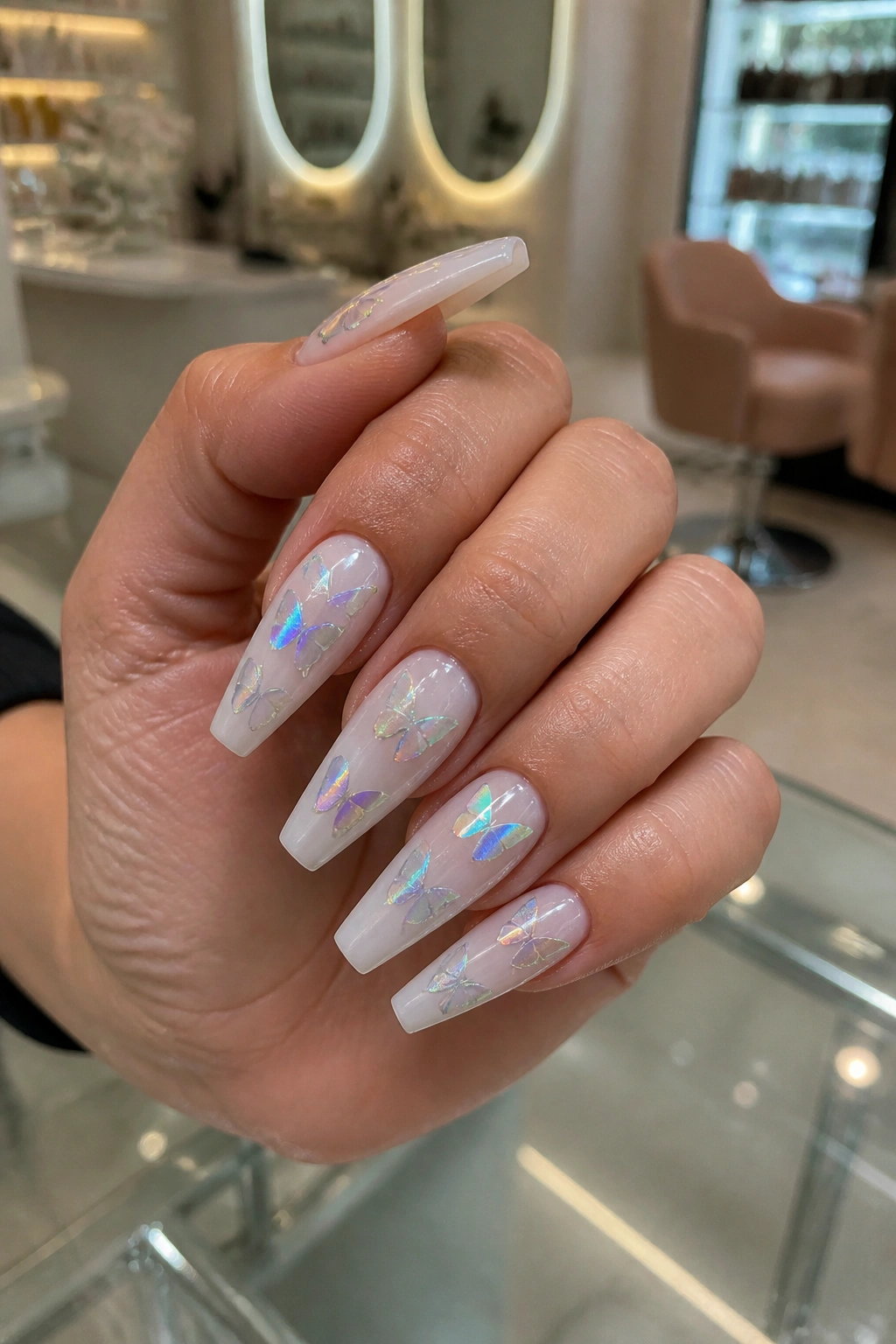 Close-up of milky white butterfly coffin nails with holographic stickers on a real hand