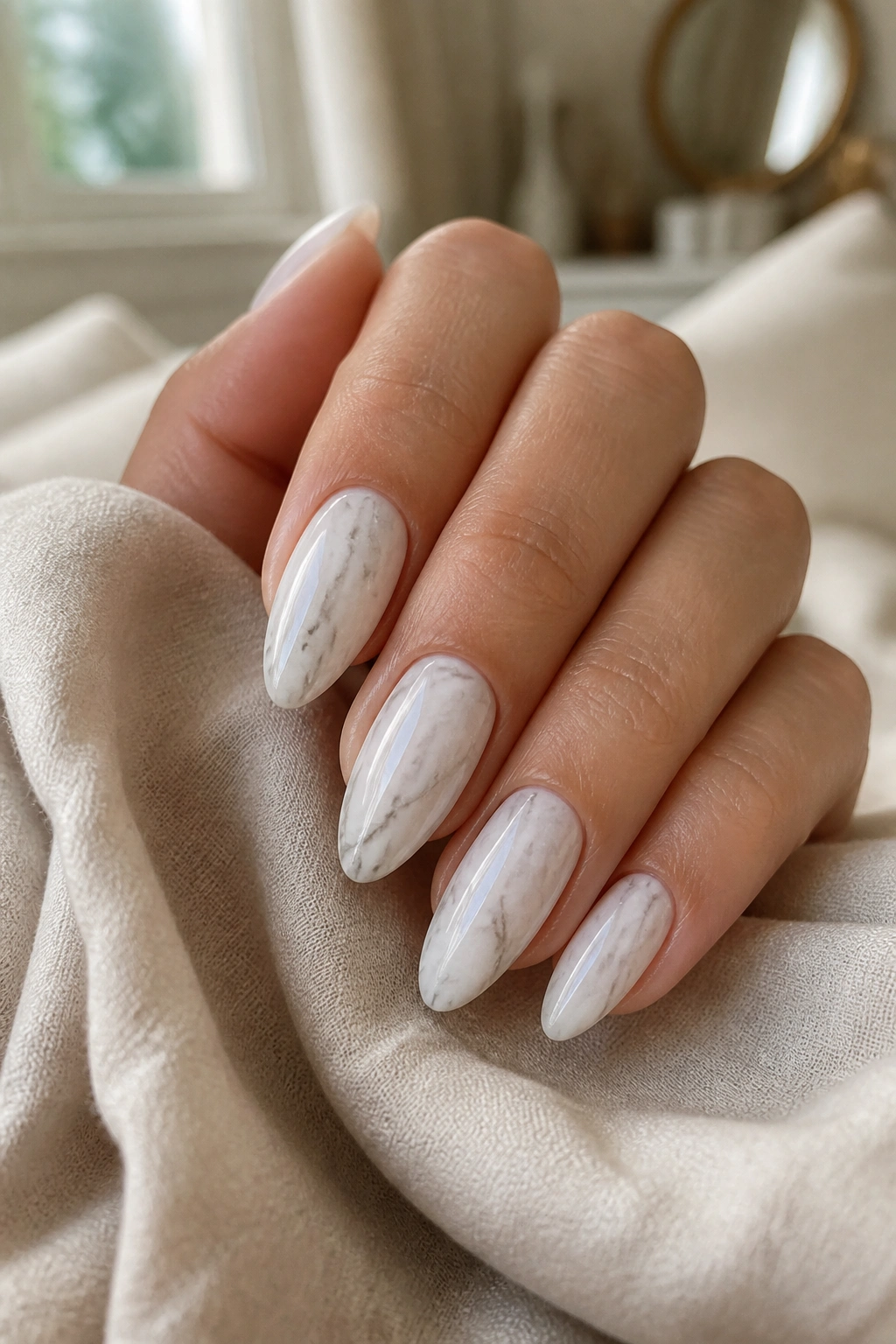 Close-up of almond nails with milky white marble and soft gray veins on a real hand
