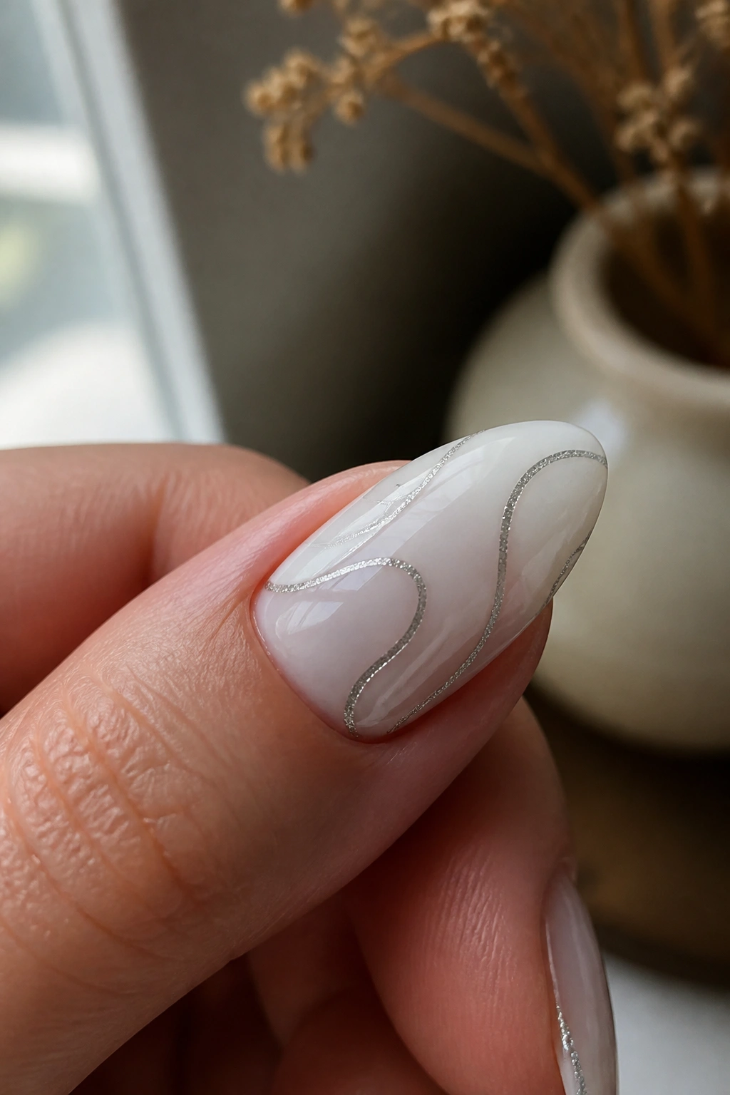 Almond nail with milky white base and silver swirls