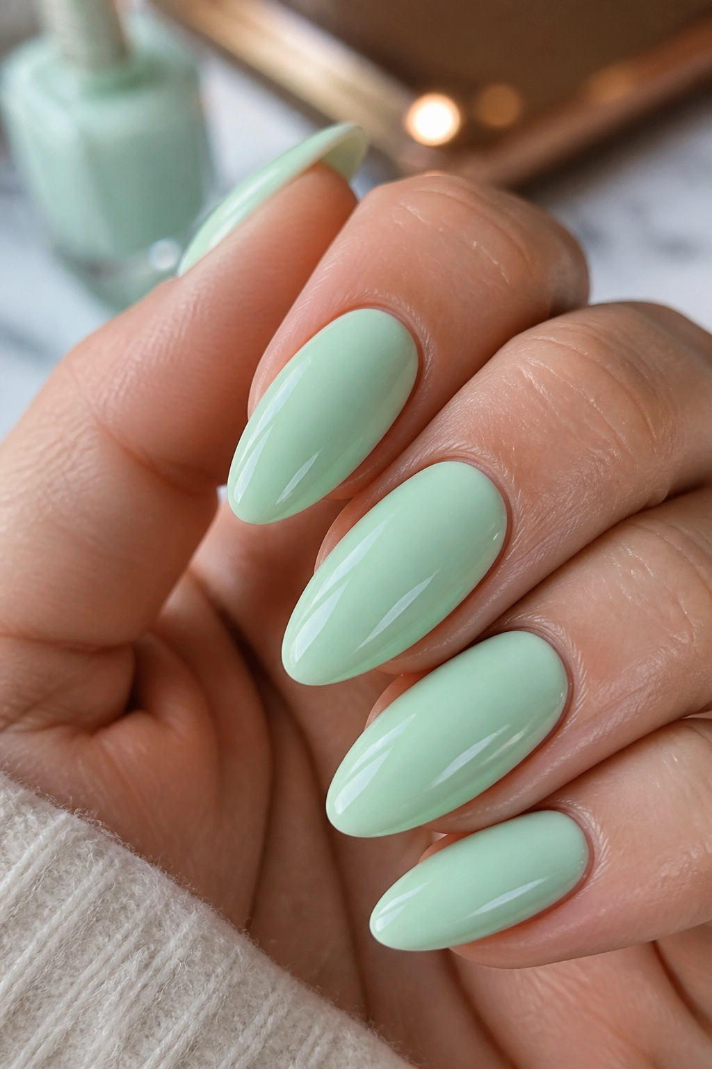 Close-up of mint green almond nails with glossy finish on a real hand