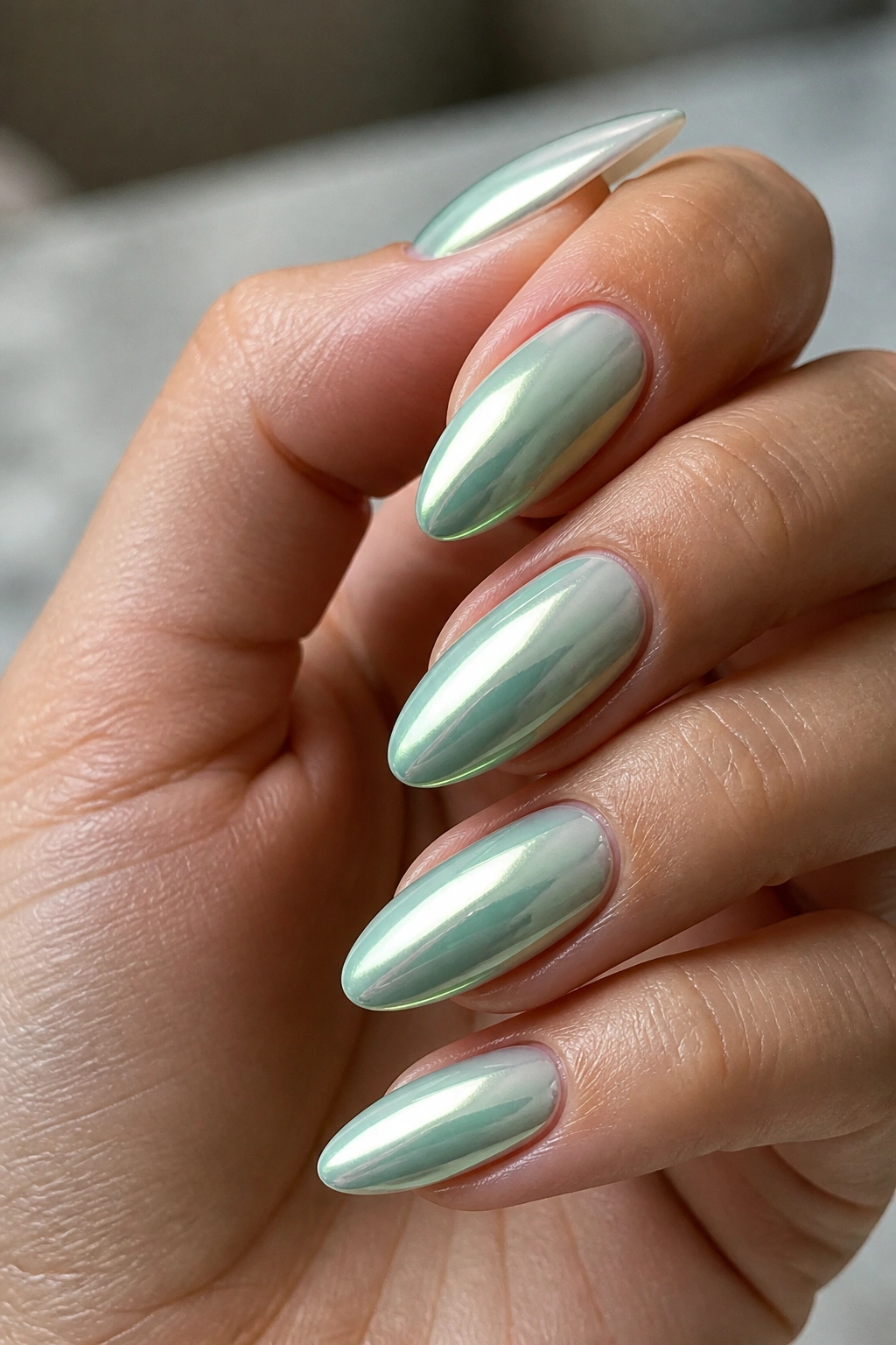 Close-up of mint chrome almond nails on a real hand