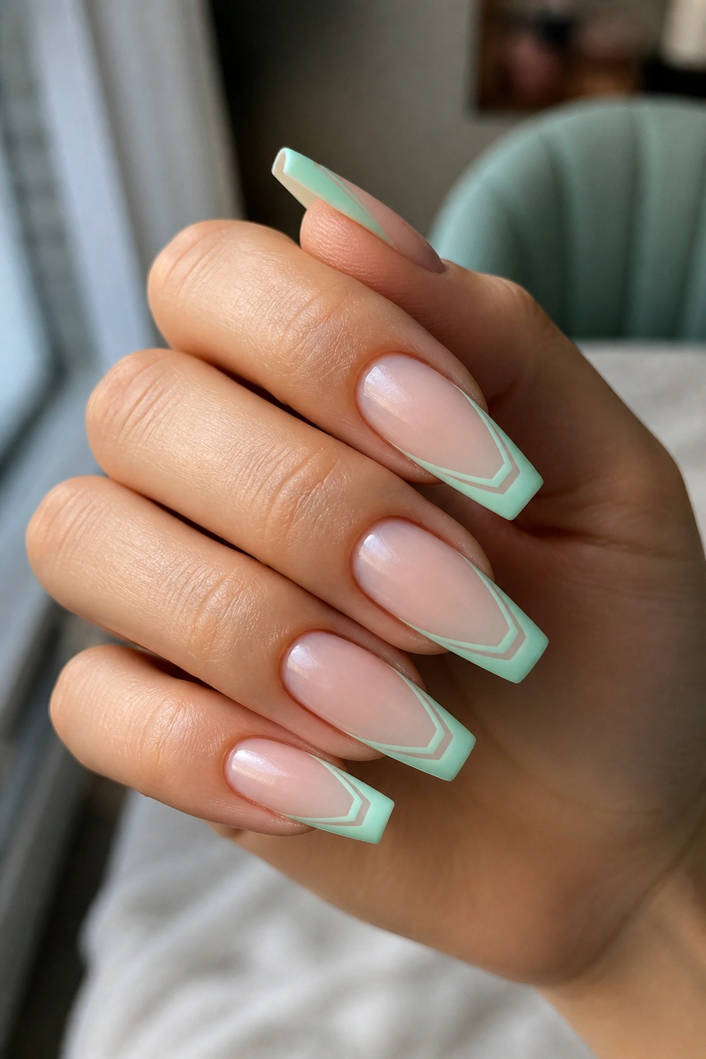Close-up of real hand with coffin nails featuring mint green double-line French tips