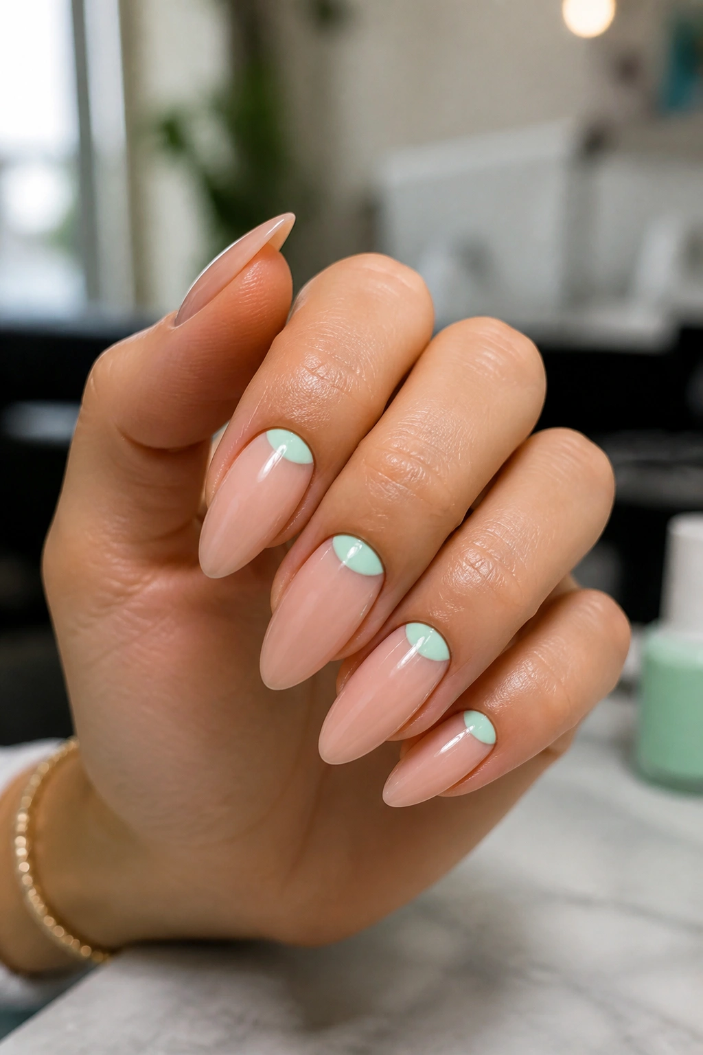 Close-up of almond nails with mint half-moon designs on nude base