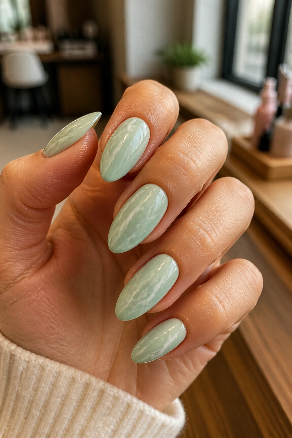 Close-up of almond nails in mint marble with white veins on a hand