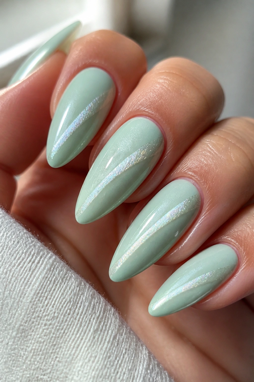 Almond nails with pale mint base and diagonal cat-eye shimmer