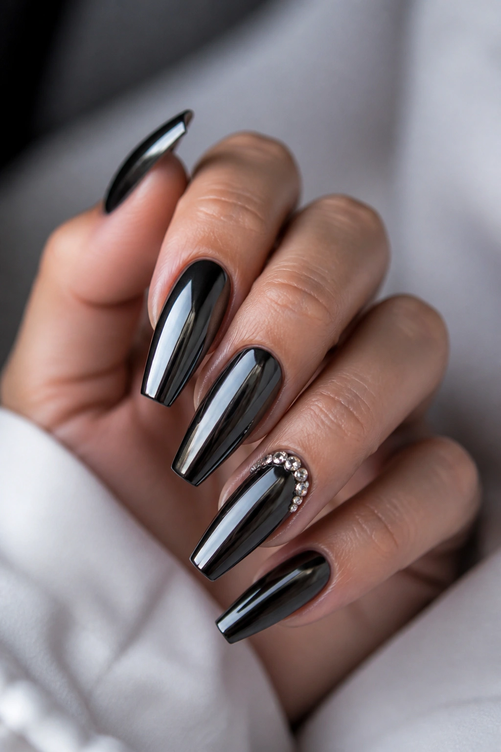Close-up of mirror chrome coffin nails with crystal accents