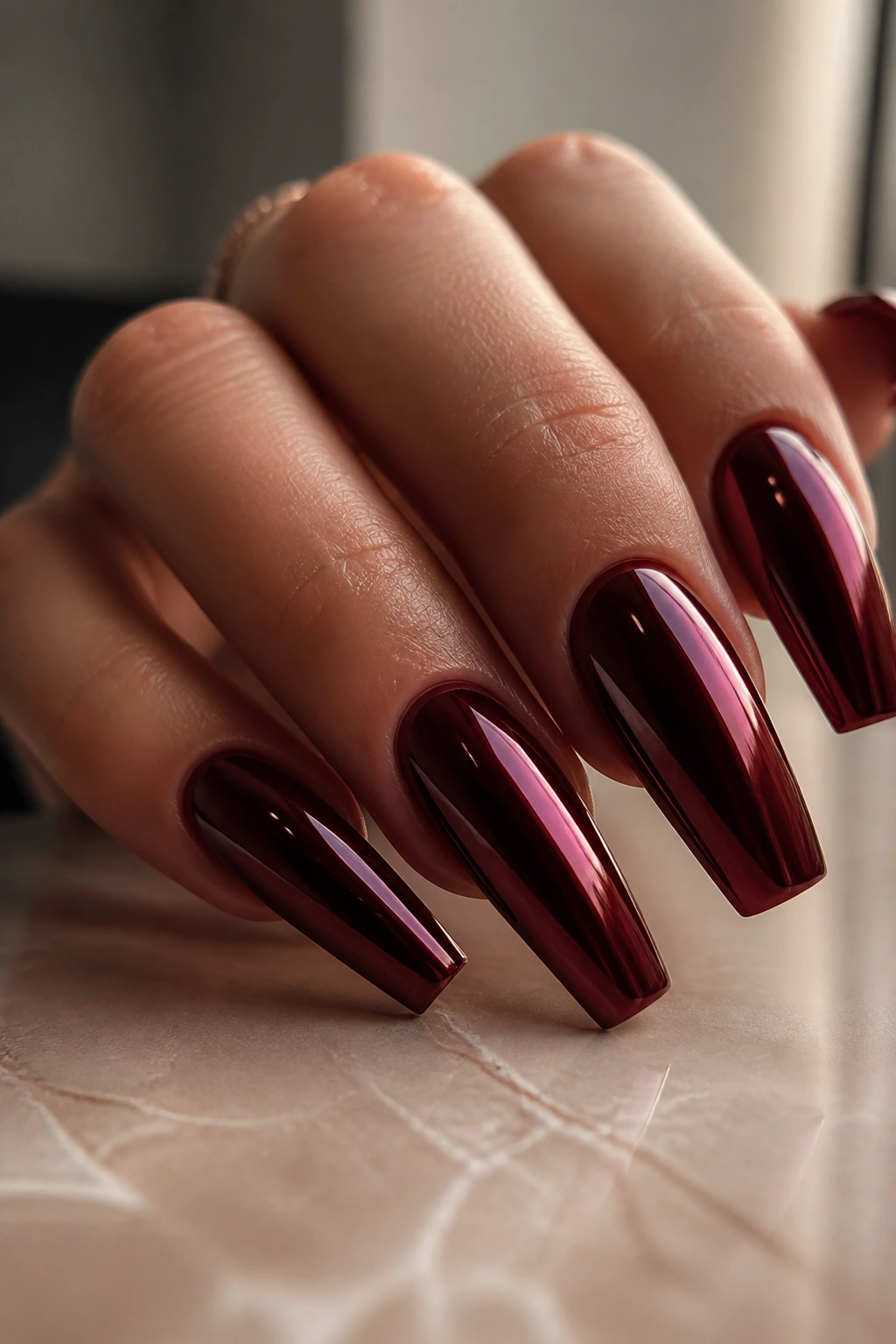 Close-up of mirror-finish maroon coffin nails on a real hand