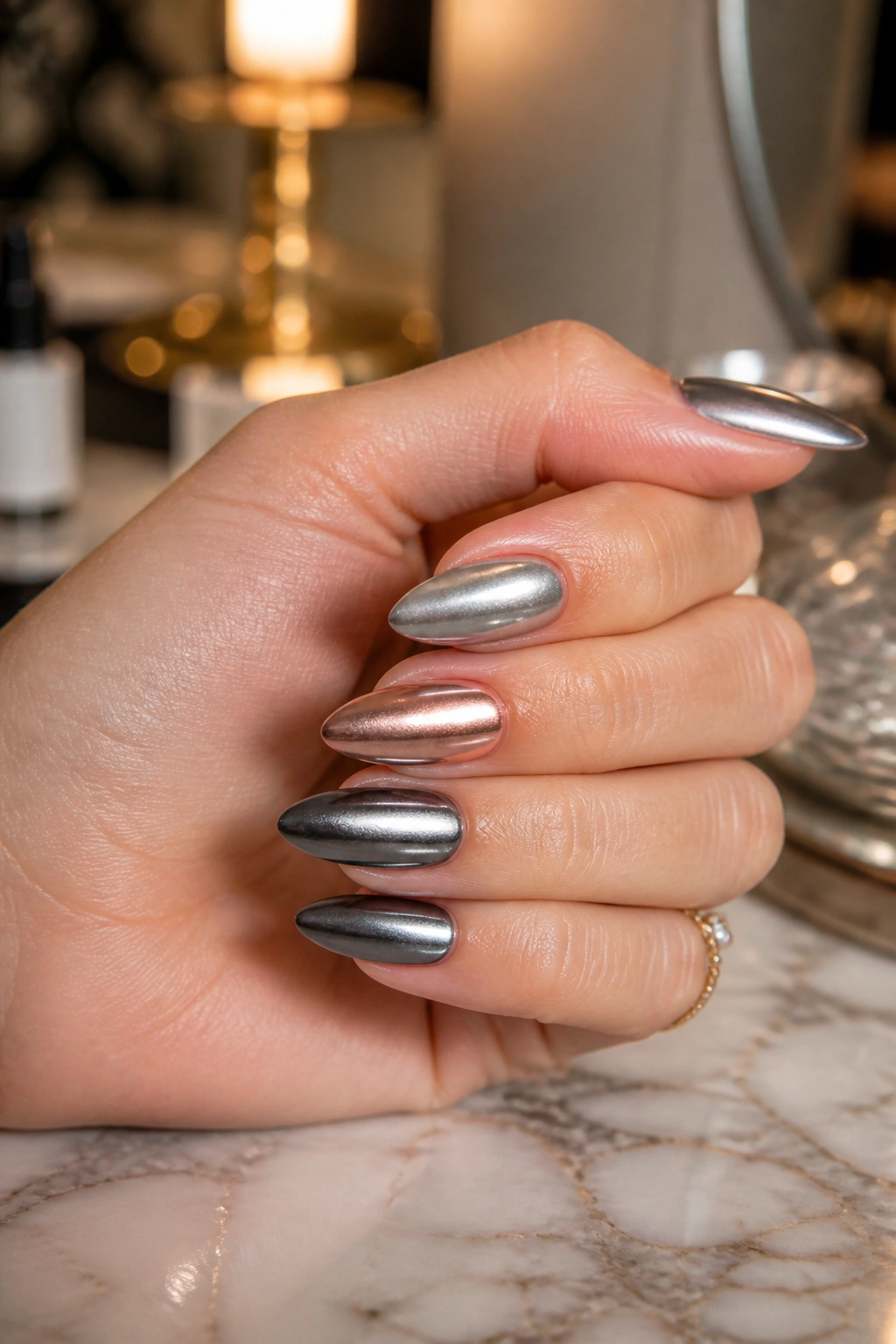 Close-up of a hand with almond nails in mixed-metal chrome finishes