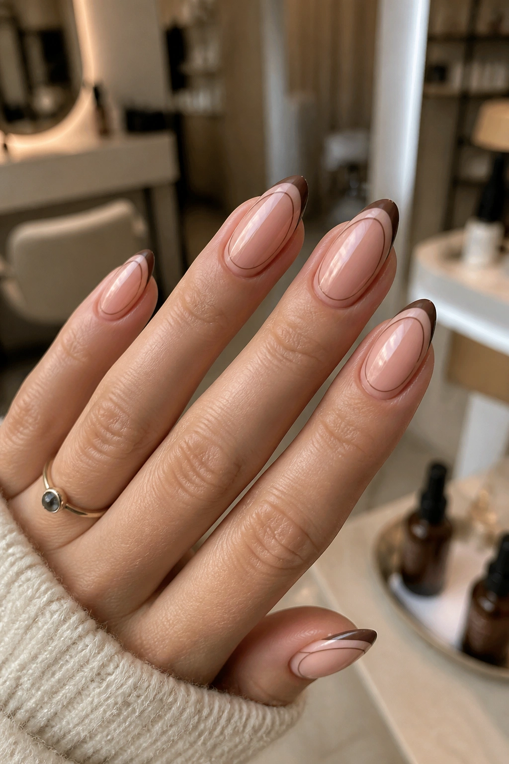 Close-up of almond nails with mocha double-lined French tips on a sheer base