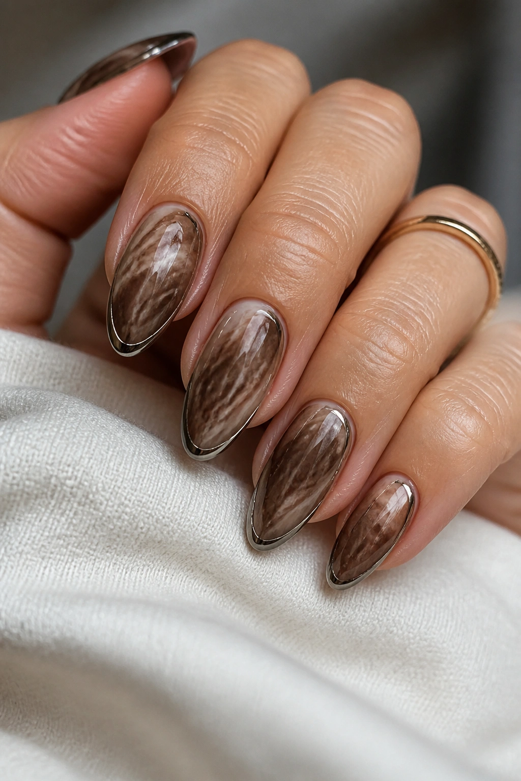 Close-up of mocha marble nails with chrome outline on almond nails