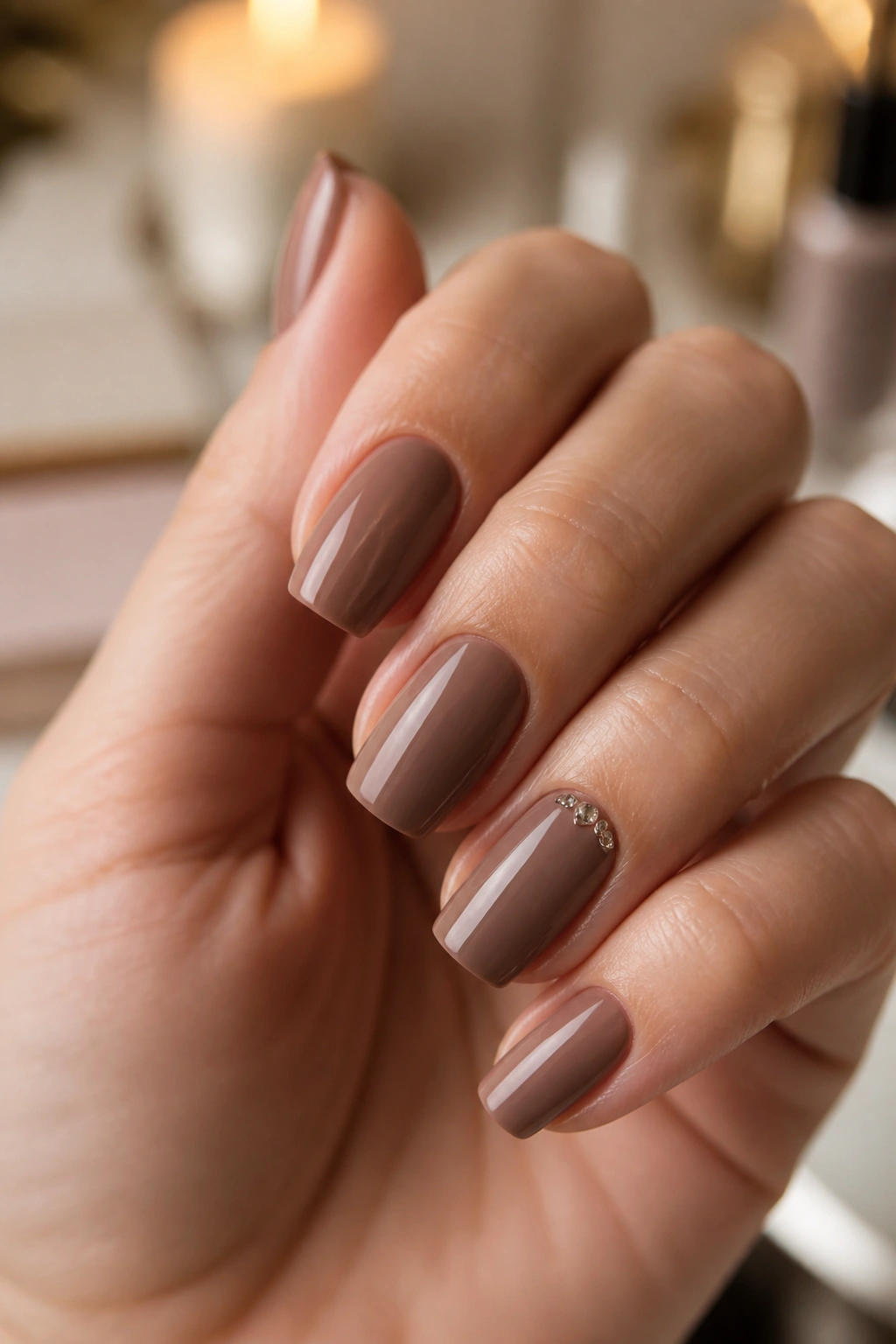 Close-up of hand with mocha coffin nails and tiny cuticle crystals on accent nail