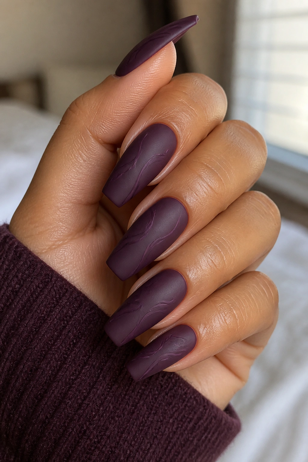 Close-up of satin mulberry coffin nails with tonal purple line art