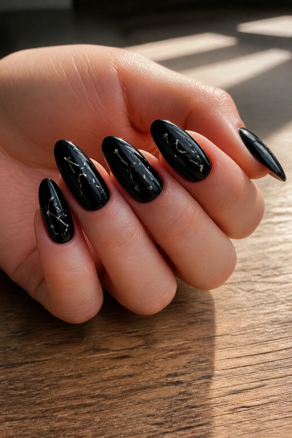 Close-up of almond nails with silver constellation dots on a black base