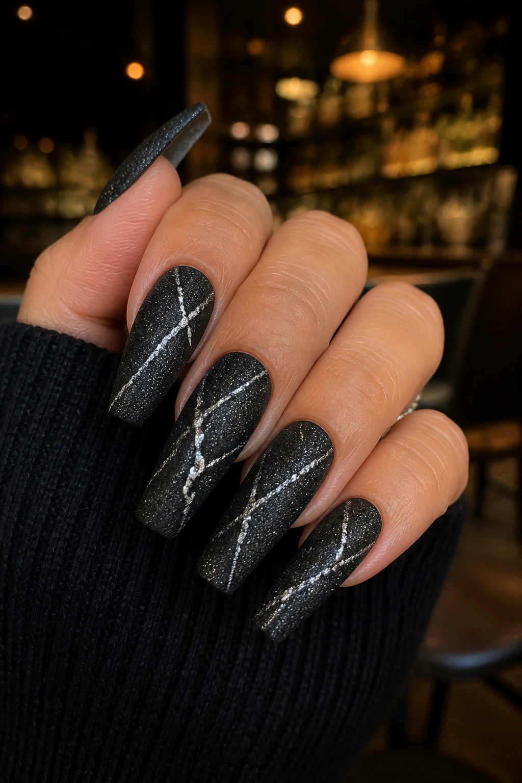 Close-up of matte black coffin nails with silver foil cracks