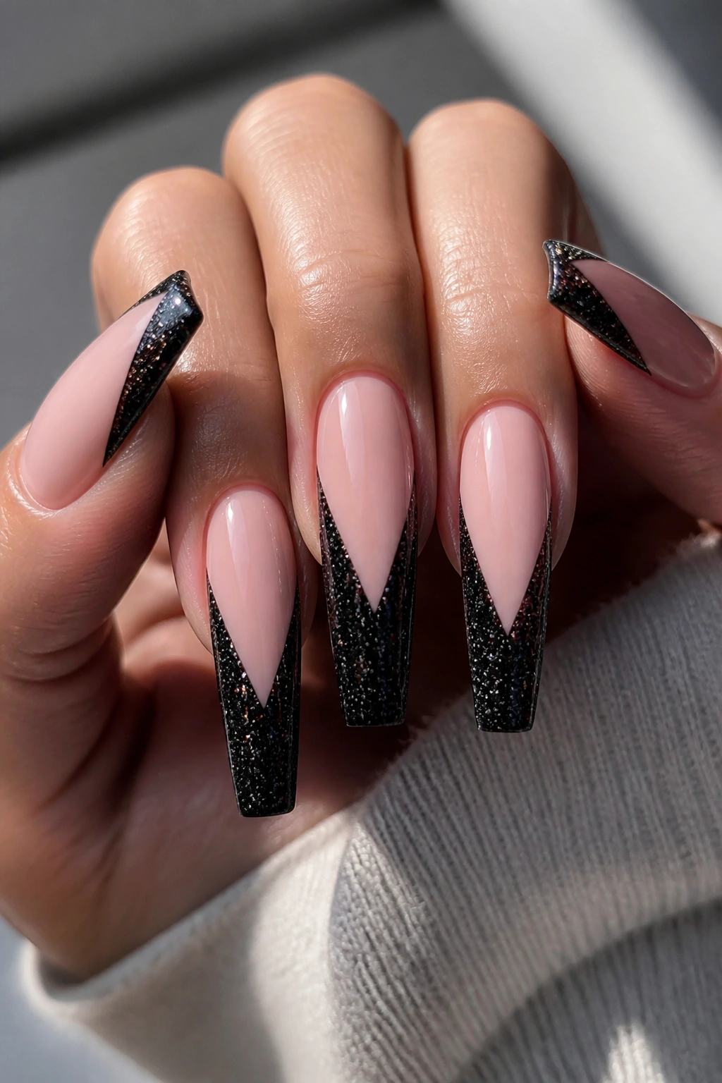 Close-up of deep V black glitter French tips on a nude base