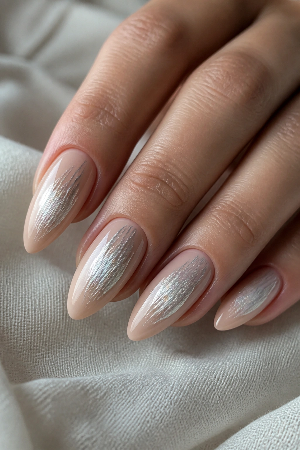 Close-up of nude almond nails with brushed silver texture