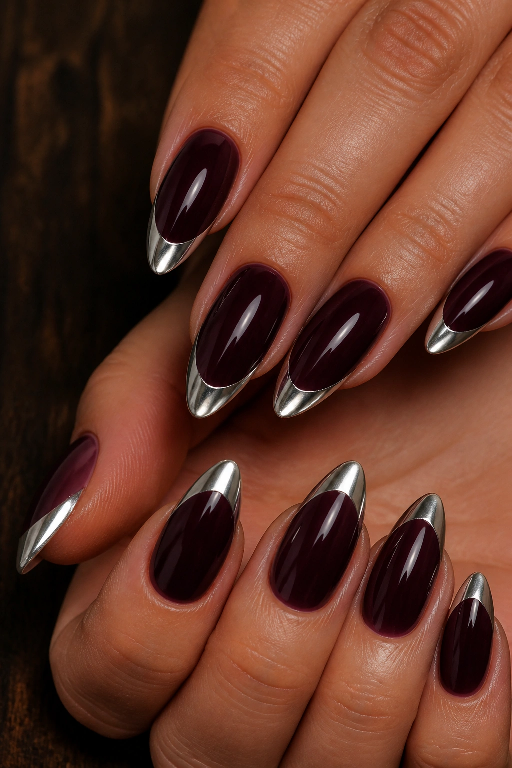 Close-up of almond nails with silver chrome tips over burgundy base