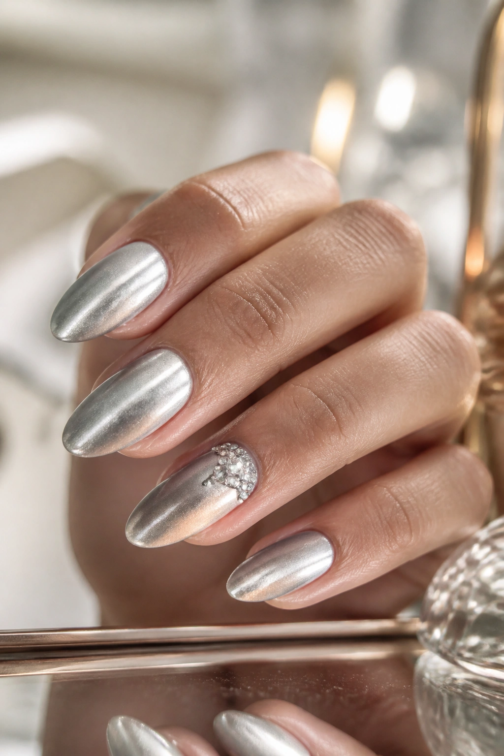 Close-up of almond nails with a crystal accent near the cuticle on a silver base