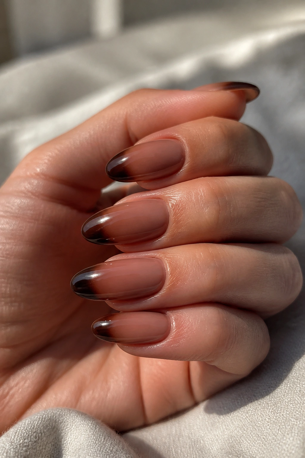 Close-up of almond nails with two-tone brown gradient tips