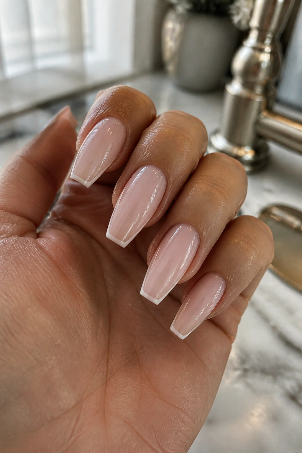 Close-up of a real hand showing coffin nails with milky base and micro white tip in natural light