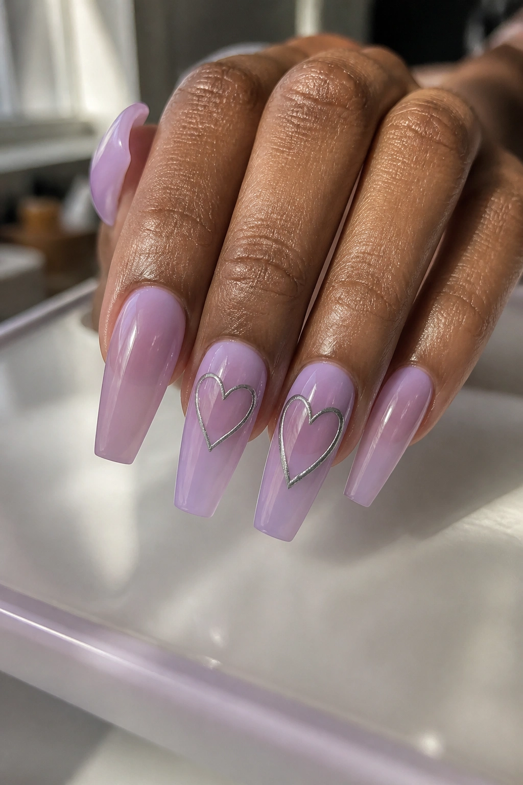 Close-up of lavender jelly coffin nails with silver heart outlines