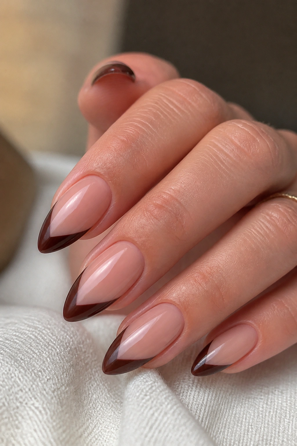 Close-up of almond nails with smoky V-cut brown French tips